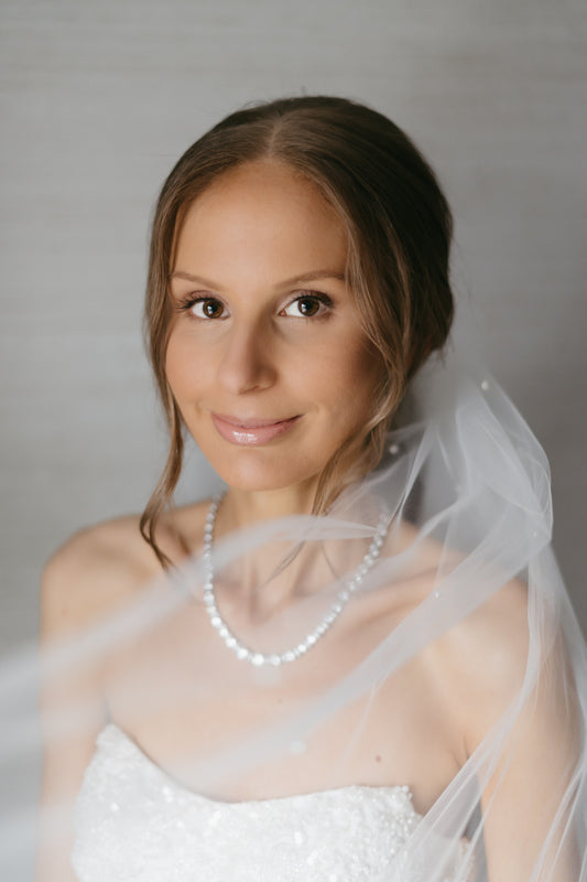 ponytail updo on bride with tulle pony hair with scattered pearls